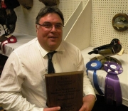 Terry Winter holding an award plaque with ribbons